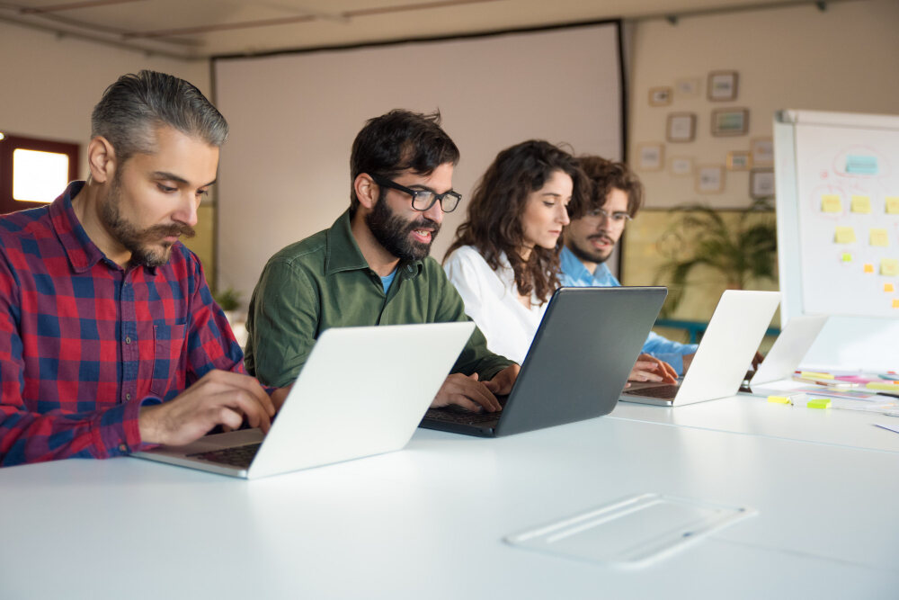 Quatro pessoas trabalhando em conjunto com os seus notebooks